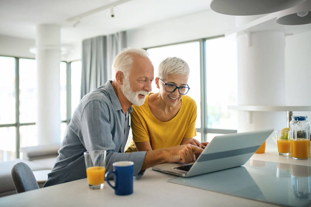 Happy couple researching investment options on laptop