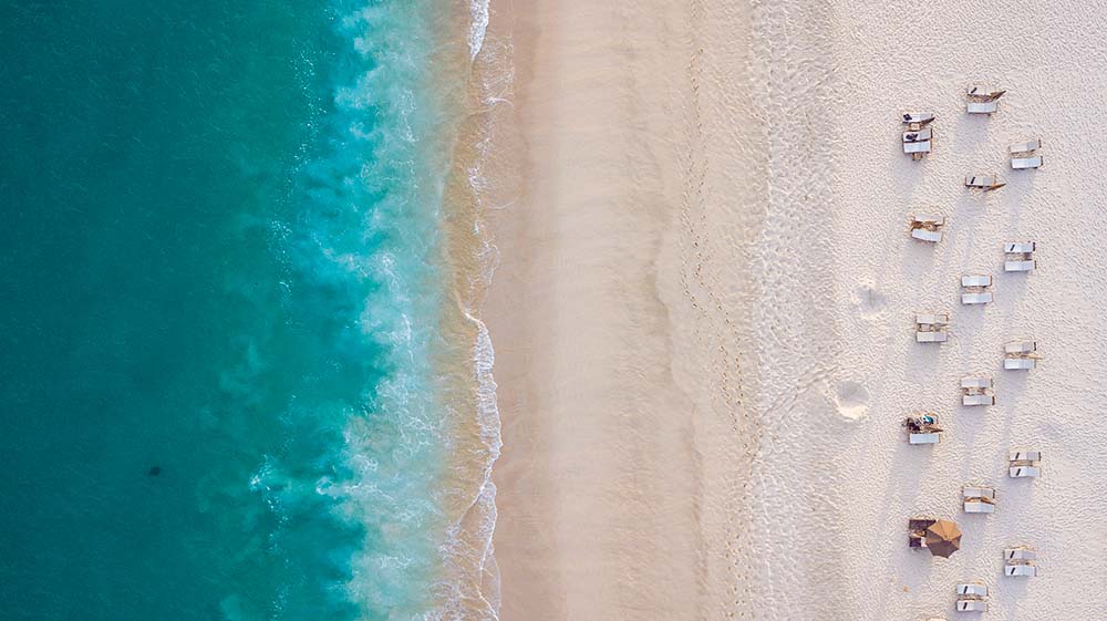 Aerial image of beach with people on holiday on deck chairs