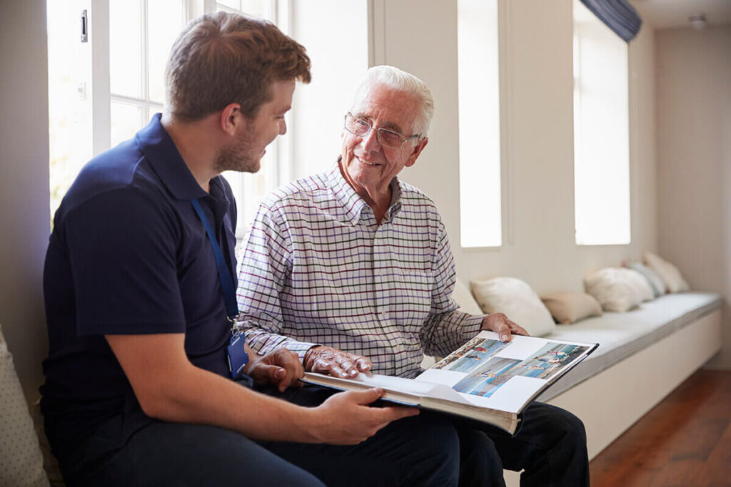 Elderly man looking through photo album memories with young male