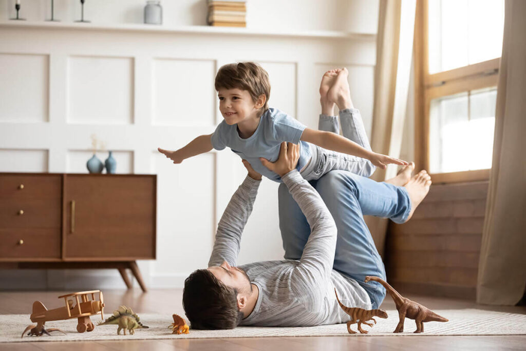 Father playing with his young son happily in their home
