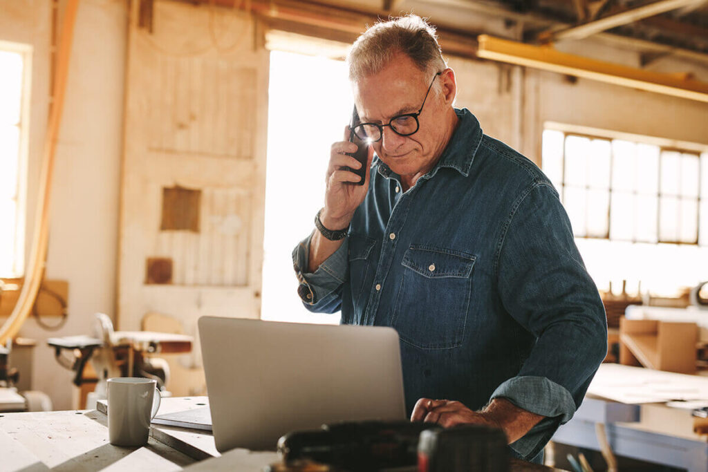 Small business owner working on laptop and phone in studio office